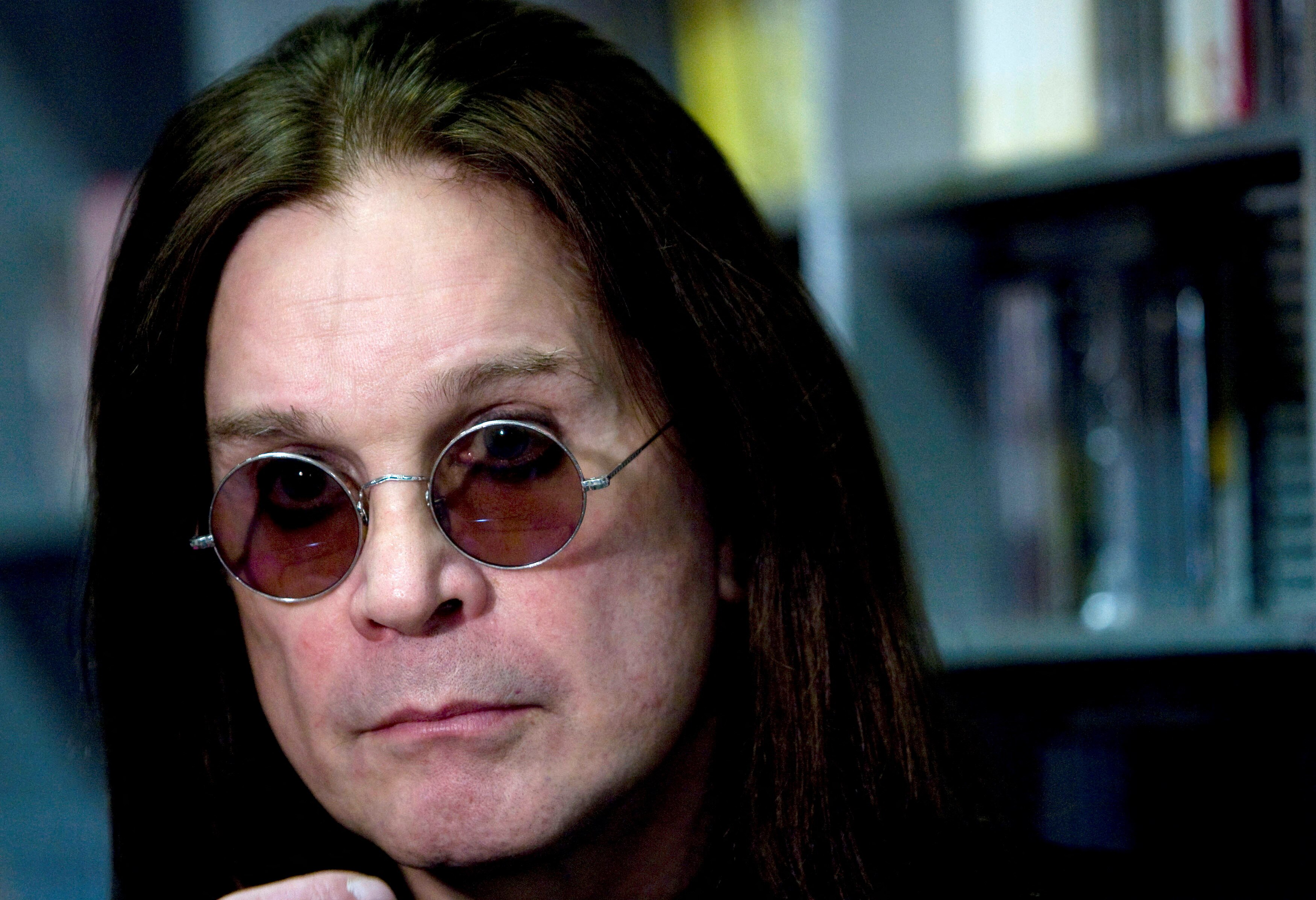 Close up image of musician ozzy osbourne while he is wearing blue circular sunglasses