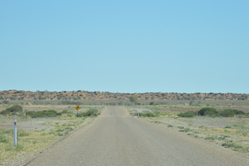 A bitumen road stretching out into an isolated landscape.
