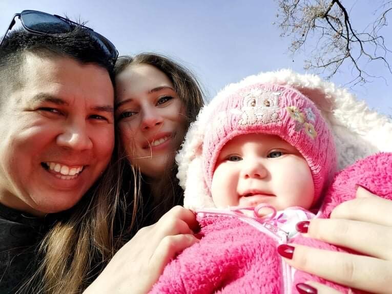 A close up photo of a man and woman and daughter in pink beanie. 