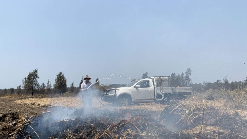 A fire smoulders under a mound of earth.