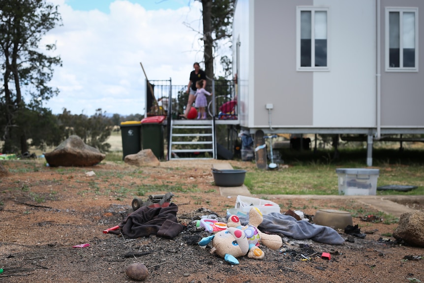 rubbish and toys in foreground and demountable home on stilts in background