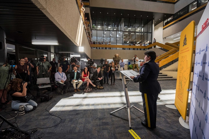 A police officer is seen from behind as she gives a press conference to journalists