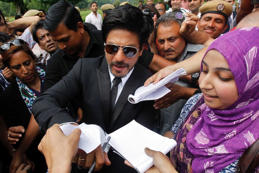Fans try to get autographs by Bollywood actor Shah Rukh Khan.