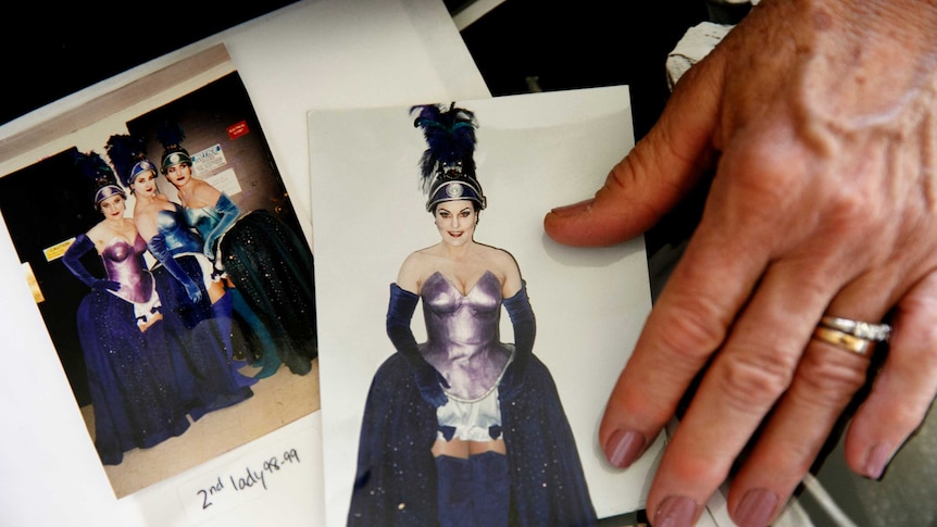A women's hand points to old photos of women dressed in opera costumes.
