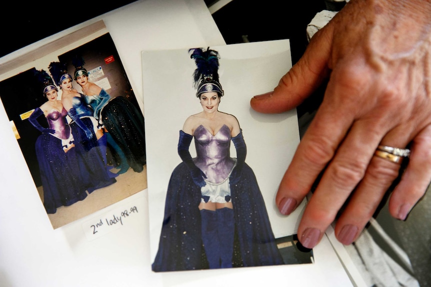 A women's hand points to old photos of women dressed in opera costumes.