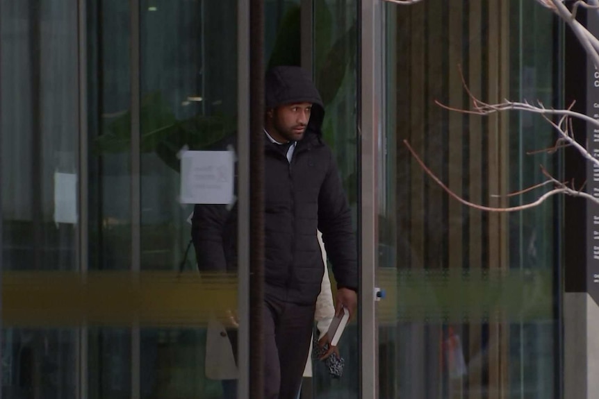 A man wearing a hood walks out of the ACT Magistrates court.