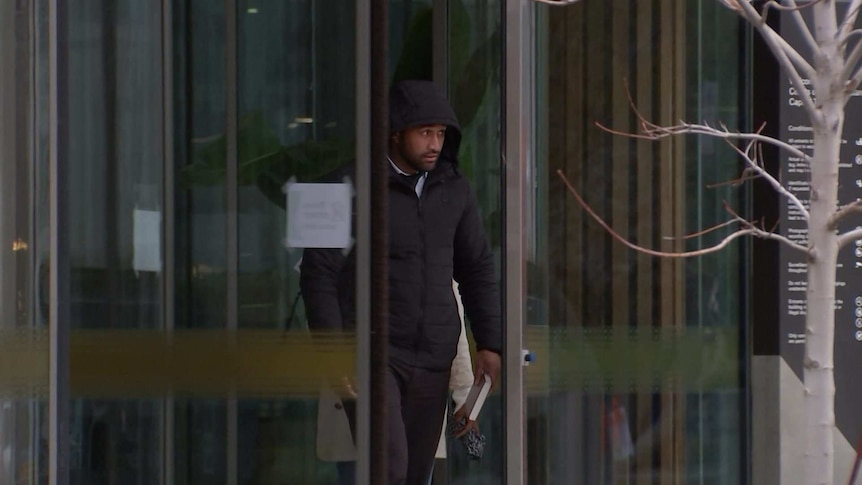 A man wearing a hood walks out of the ACT Magistrates court.
