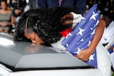 Myeshia Johnson, wife US Army Sergeant La David Johnson, kisses his coffin at a graveside service. She is holding a US flag.