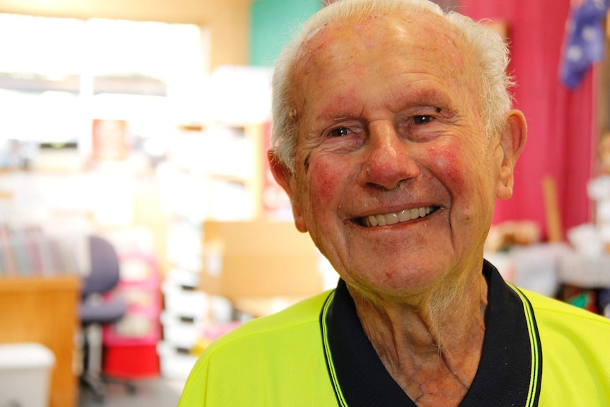 A head and shoulders shot of a smiling elderly man in a high-vis shirt.