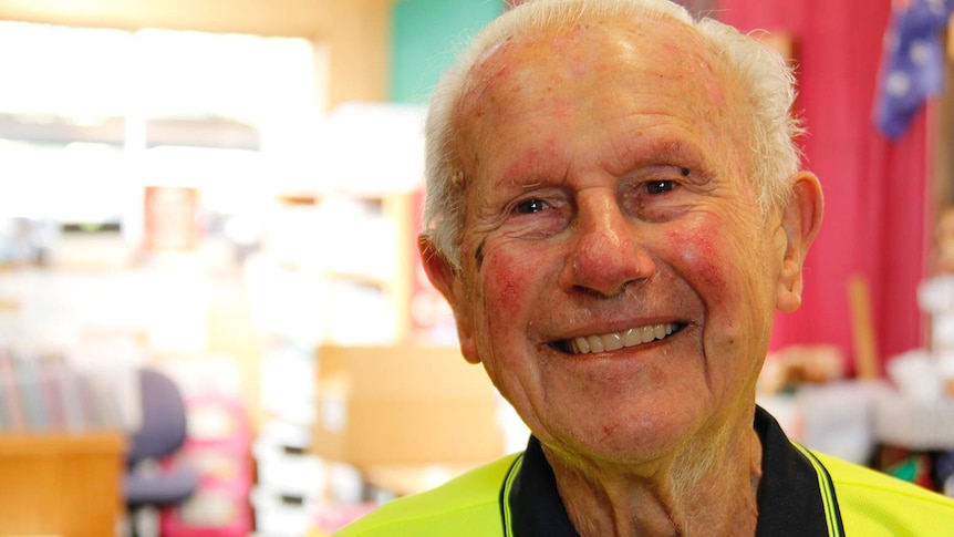 A head and shoulders shot of a smiling elderly man in a high-vis shirt.