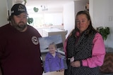 A man and a woman holding a photo of a child.