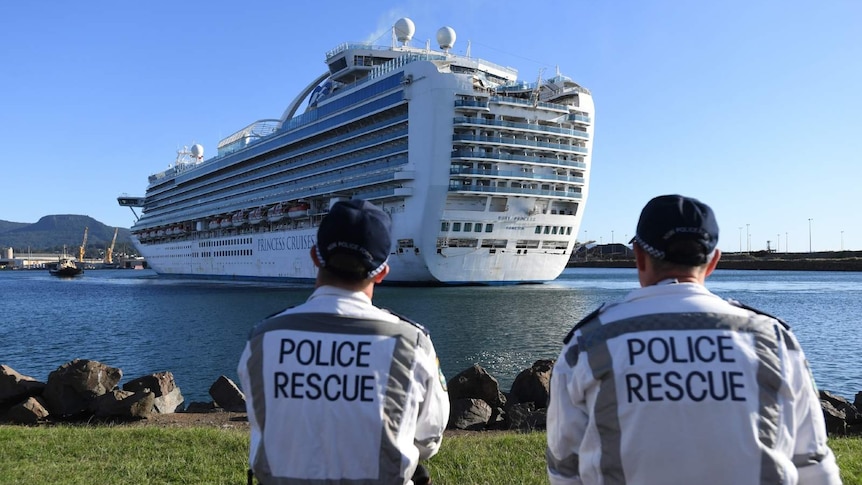two police rescue officers looking at a cruise in a harbour
