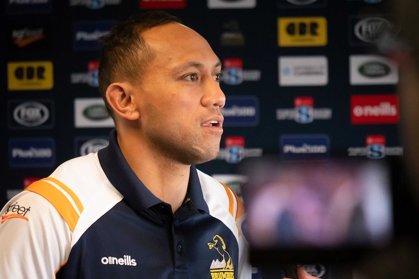 Christian Lealiifan, dressed in his Brumbies jersey, speaks to TV cameras at a press conference.