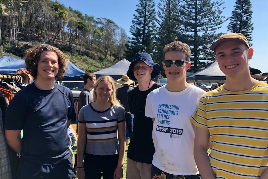 Five teenagers smiling in the sun.