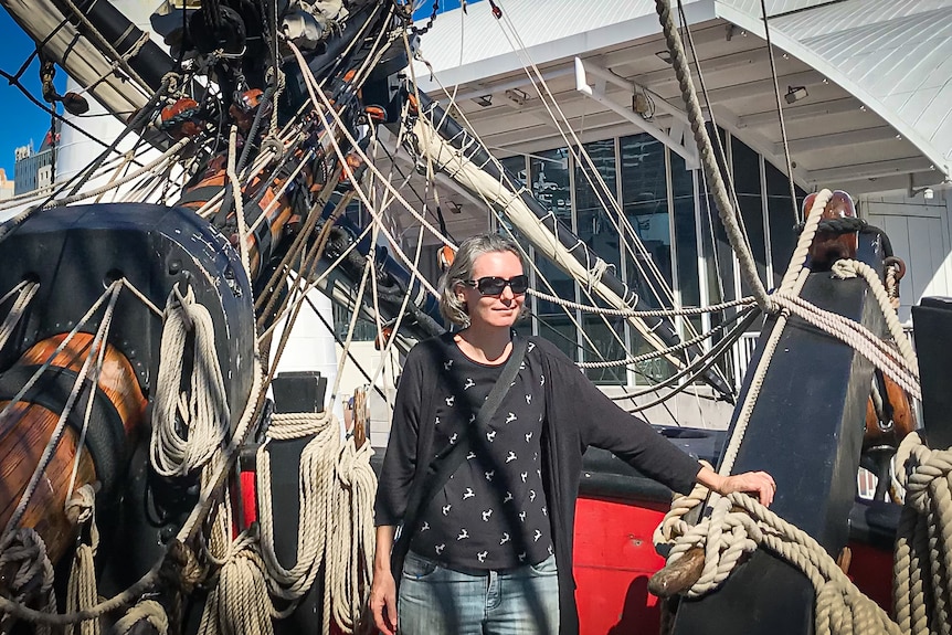 Woman in sunnies on deck of a sailing ship.