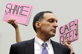 Protesters hold signs behind Richard Fuld, chairman and chief executive of Lehman Brothers Holdings.