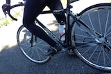 Cyclist on a bike, showing the cyclist's legs and two wheels of the bike.