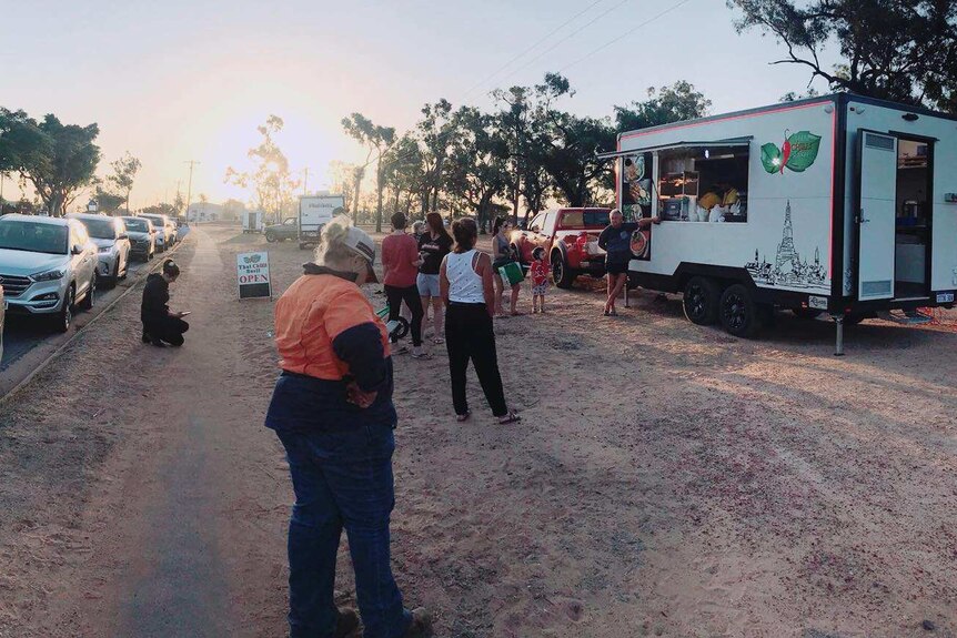 A line of people waits outside a food truck