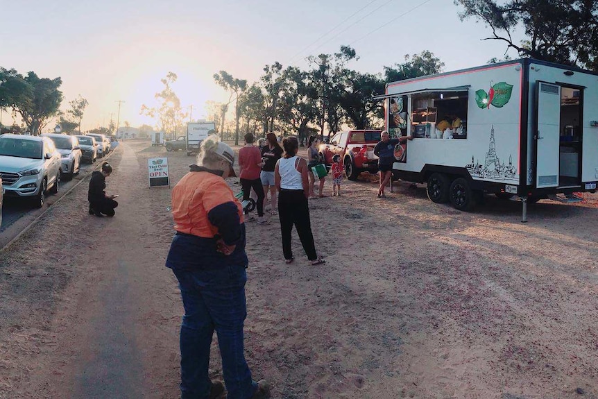 A line of people waits outside a food truck