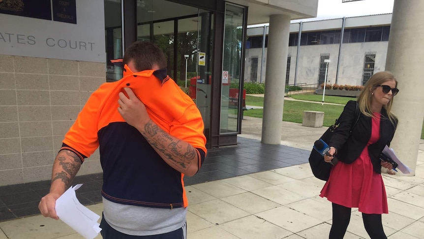 Harley Stott covers his face after appearing in the ACT Magistrates Court in relation to a shooting in Gowrie last year. (February 5 2016)