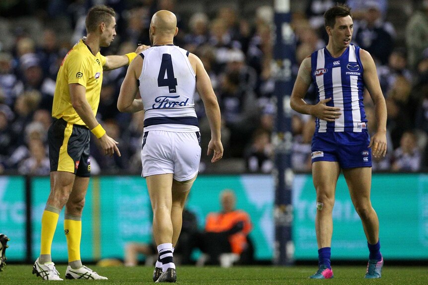An AFL player talks to the umpire after giving away a free kick.