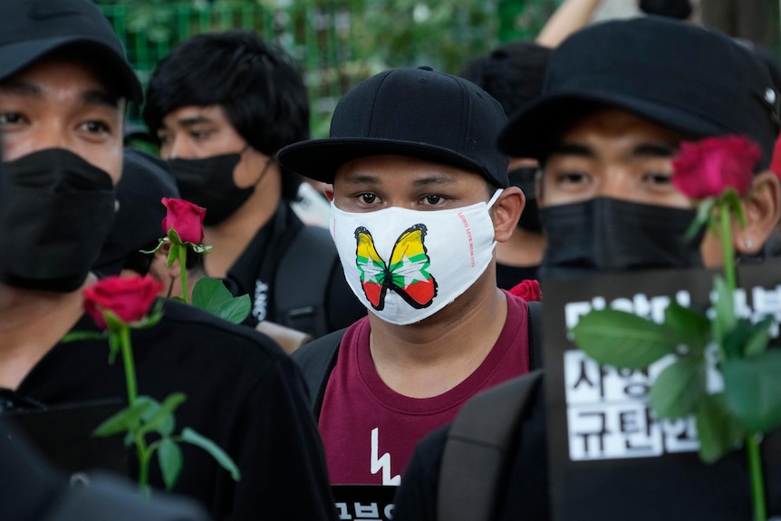 A person in a mask with a butterfly. The wings are the flag and colours of Myanmar.