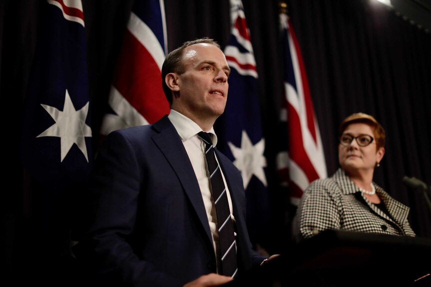 Dominic Raab and Marise Payne stand in front of UK and Australian flags addressing the media