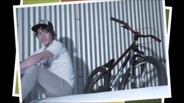 Teenage boy sits beside bicycle
