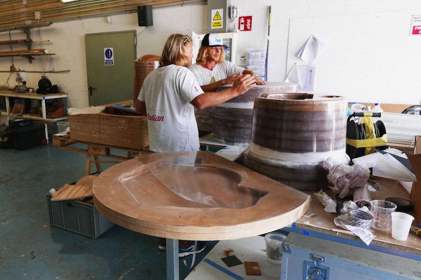 Andrew Turton and Pete Ceglinski stand in a workshop looking at a prototype Seabin.
