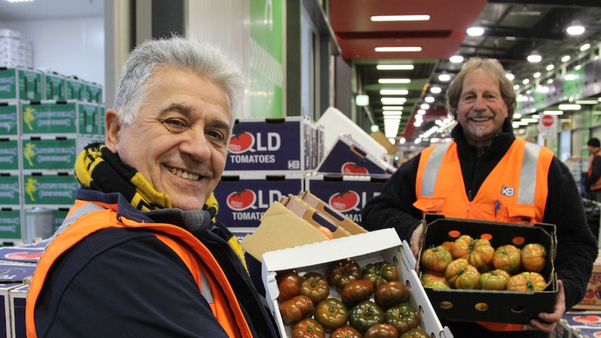 Harry Kapiris (left) and Frank Mileto hold boxes of tomatoes at the Melbourne Markets.