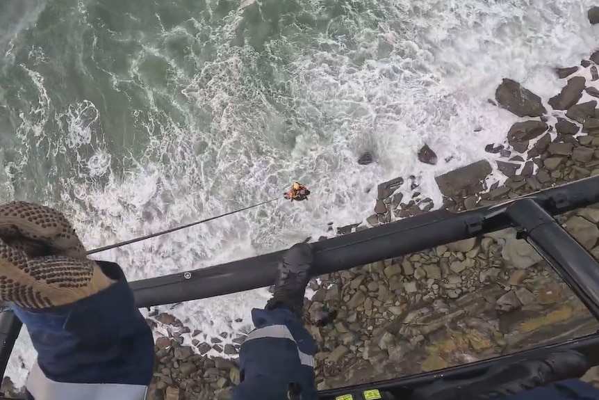 Looking down on an emergency working rescues a man and is winched onto a helicopter