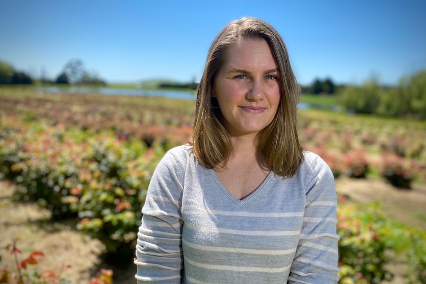 a woman is standing in a rose field staring at the camera