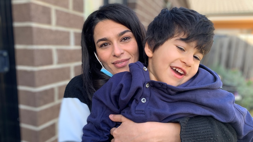 Roya Hamidavi holding her son Aiden, who is smiling playfully and looking off camera.