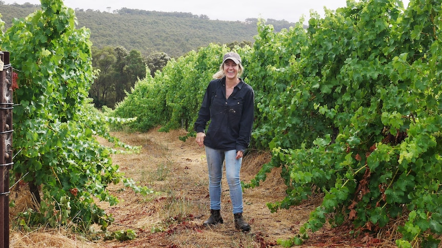 Young woman laughing in vineyard rows.