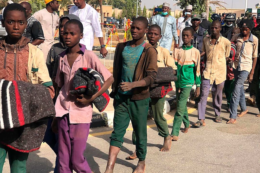 A line of Nigerian boys walking on a road.