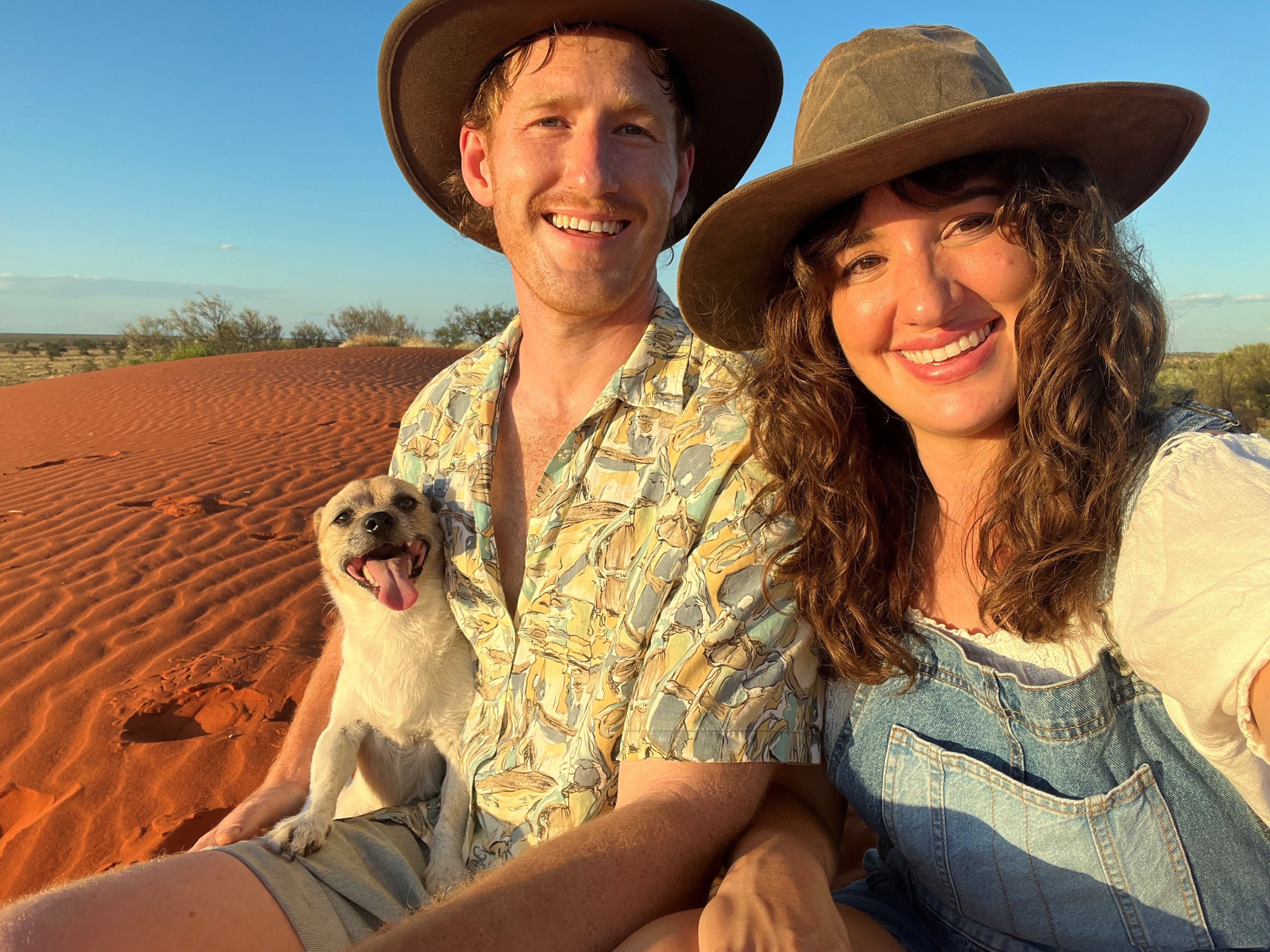 A dog, a young man and a young woman sitting in the Australian desert