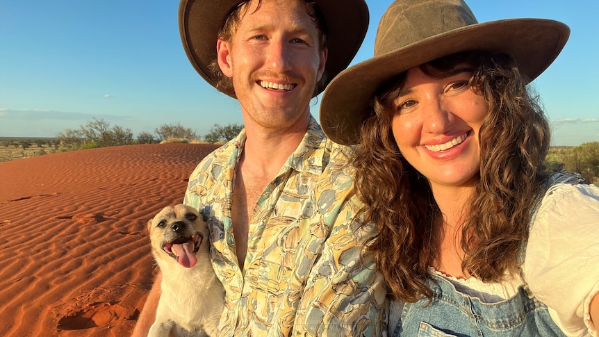 A dog, a young man and a young woman sitting in the Australian desert