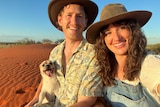 A dog, a young man and a young woman sitting in the Australian desert