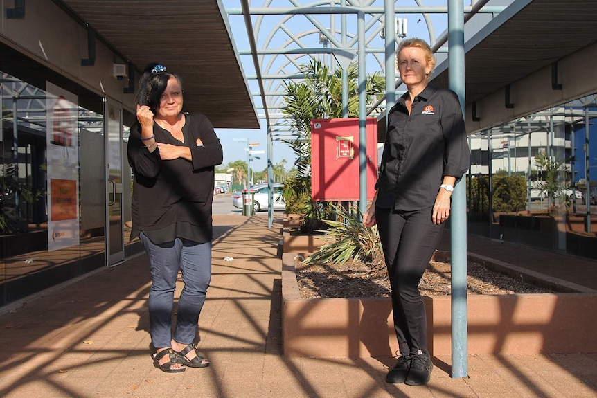 A photo of two financial counsellors standing in an alleyway in the afternoon sun.