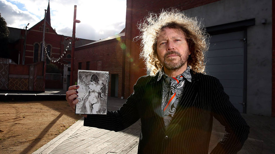 A man stands in a courtyard holding a black and white drawing of a nude woman.