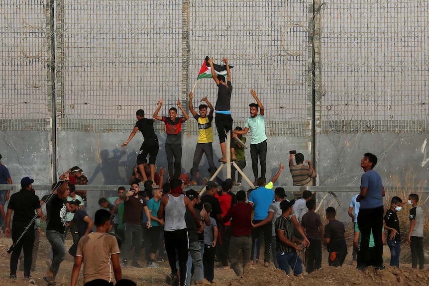 Protesters try to climb the fence of the Gaza Strip's border with Israel