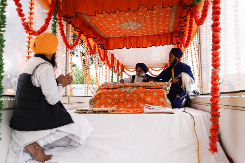 The Granthi or priest reads from the Sri Guru Granth Sahib (Holy Book) inside the mobile Gurduara (temple).