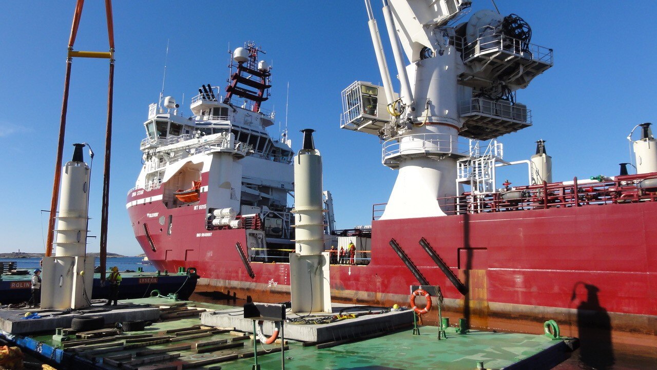 A light construction vessel with generators on the water on a blue sky day