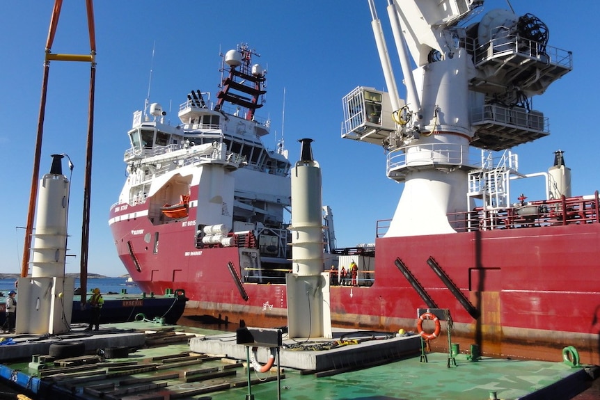 A light construction vessel with generators on the water on a blue sky day