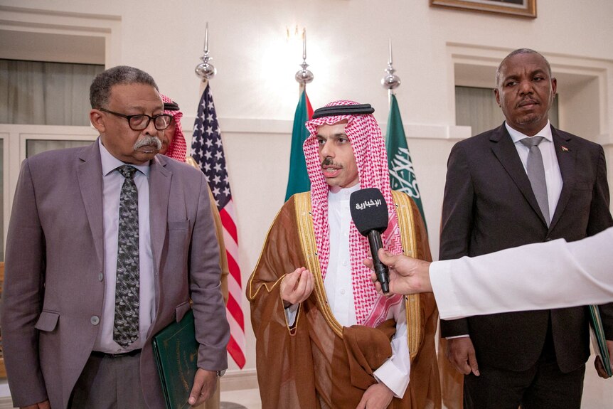 Prince Faisal bin Farhan bin Abdullah Al-Saud speaks next to representatives from Sudan army and RSF