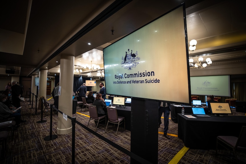 A screen inside the royal commission shows the Australian Government logo and signage.