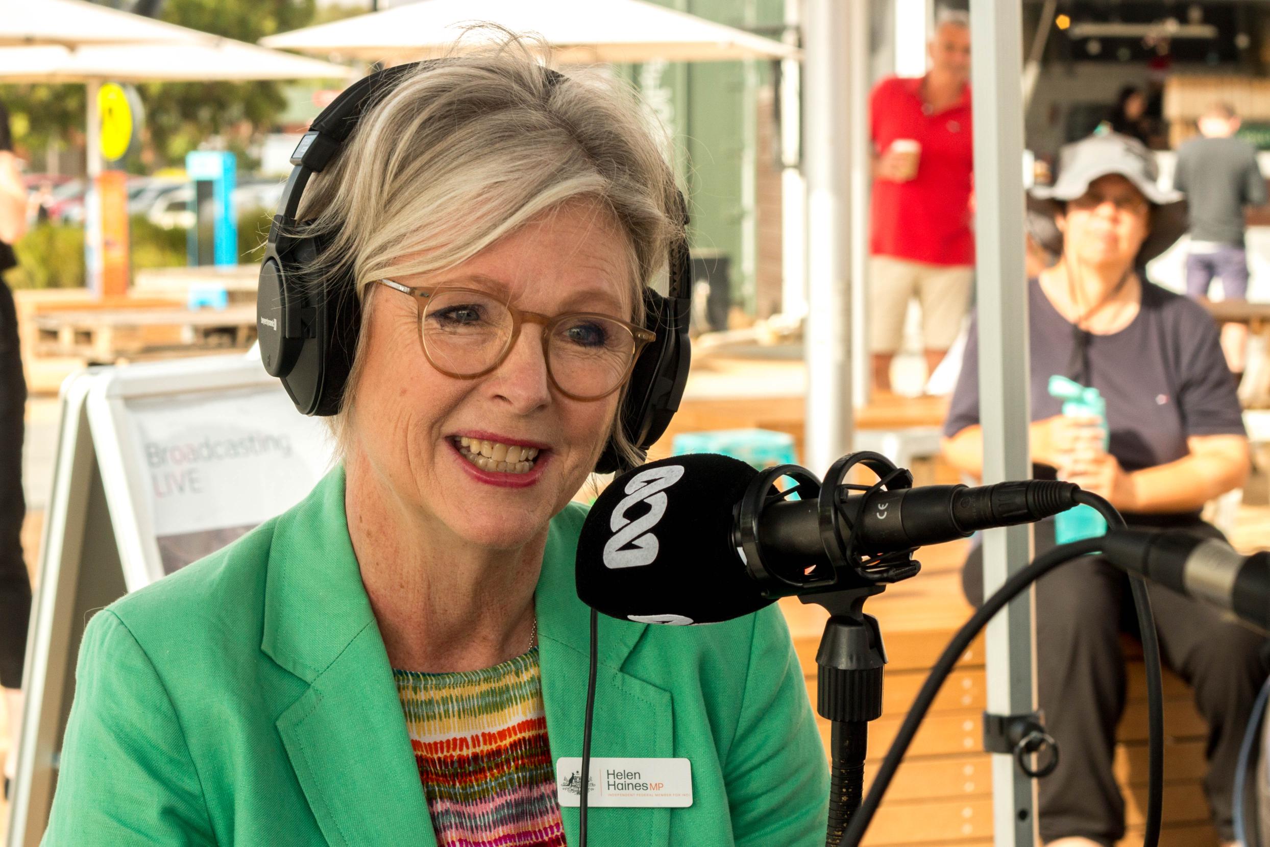 Woman in green jacket in front of ABC microphone