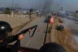 A police officer fires rubber bullets to disperse protesters during a clash in Islamabad.