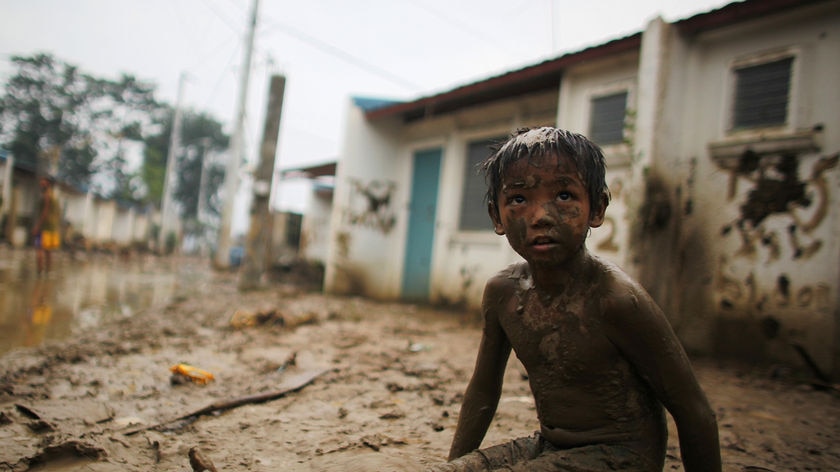 A child sits on mud caused by Typhoon Ketsana in Montalban Rizal, west of Manila on October 2, 2009.