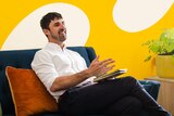 Psychologist Chris Cheers sitting on a couch, smiling mid-conversation. 